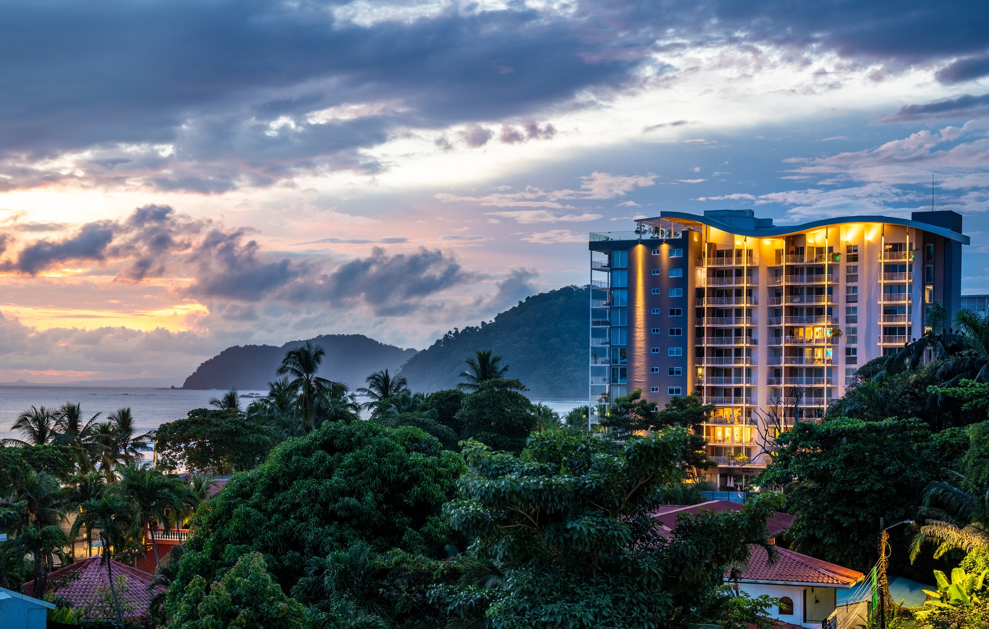 Torre residencial al atardecer entre montañas y selva